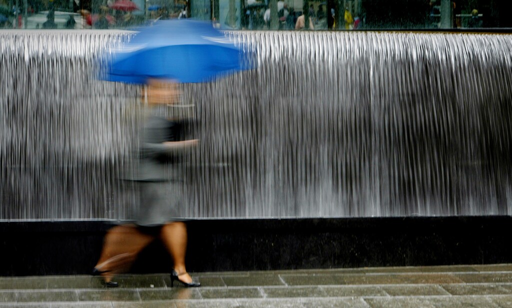 A pedestrian hurries through the rain in front of a fountain in central Sydney November 9, 2004. Australia's weather is changing, weather scientists said at a climate and water forum this week, blaming growing clouds of carbon dioxide from industry, changes in Antarctic circulation because of ozone depletion and natural variability. NO RIGHTS CLEARANCES OR PERMISSIONS ARE REQUIRED FOR THIS IMAGE. REUTERS/Tim Wimborne TBW/TW - RP5DRIAYDTAA