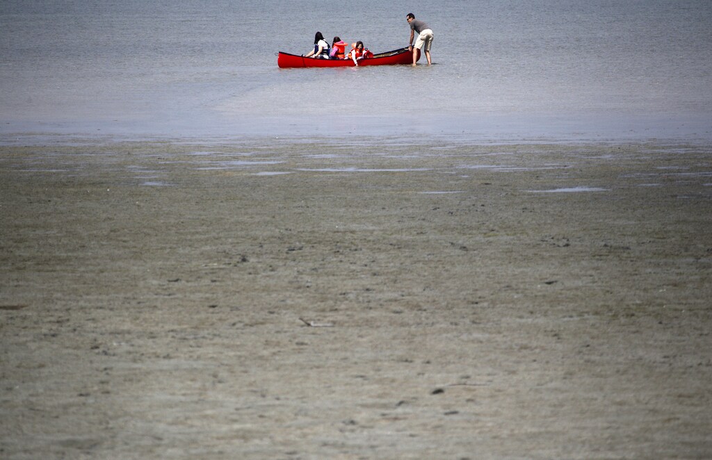 People on a canoe enjoy a sunny day on the dry banks of Lake Constance outside the village of Triboltingen, April 26, 2011. REUTERS/Christian Hartmann (SWITZERLAND - Tags: ENVIRONMENT) - BM2E74Q18PI01