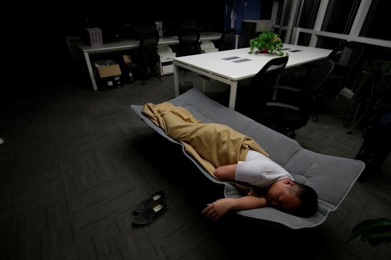 Ma Zhenguo, a system engineer at RenRen Credit Management Co., sleeps on a camp bed at the office after finishing work early morning, in Beijing, China, April 27, 2016. Office workers sleeping on the job is a common sight in China, where a surplus of cheap labour can lead to downtime at work. But in China's technology sector, where business is growing faster than many start-up firms can hire new staff, workers burn the midnight oil to meet deadlines and compete with their rivals. Some companies provide sleeping areas and beds for workers to rest during late nights.