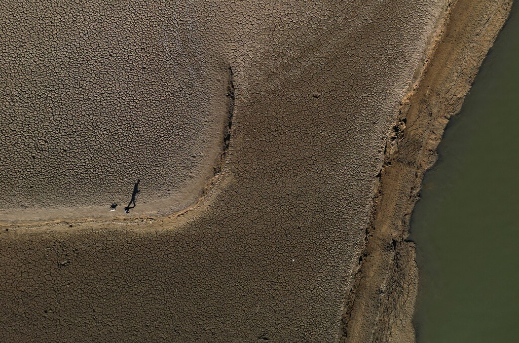 A man walks his dog at a reservoir in the province of Catalonia, Spain.