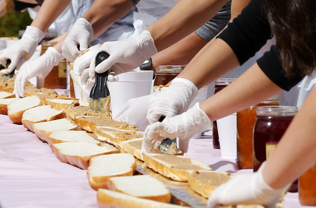Students from Escondido Charter High School work to construct a 51-foot (16m) peanut butter and jelly sandwich in the hopes of setting a world record by using the most flavors of jams and jellies on National Peanut Butter and Jelly Day in Escondido, California April 2, 2014. REUTERS/Mike Blake (UNITED STATES - Tags: SOCIETY HEALTH EDUCATION) - GM1EA430E3N01