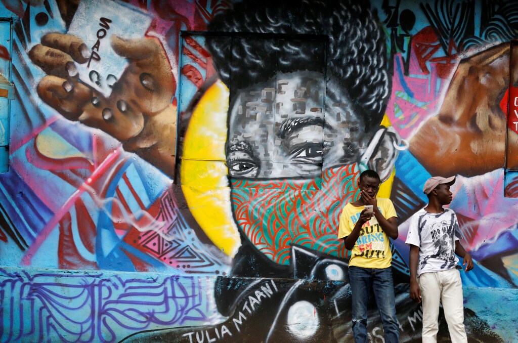 Residents stand in front of a graffiti by Mathare Roots's youth group advocating against the spread of the coronavirus disease (COVID-19), at the Mathare Valley slum, in Nairobi, Kenya April 19, 2020. Picture taken April 19, 2020. REUTERS/Thomas Mukoya - RC2CAG9HK53O