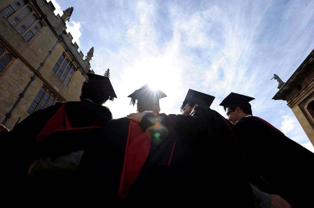 A group of graduates gather outside the Sheldonian Theatre to have their photograph taken after a graduation ceremony at Oxford University, Oxford, England, May 28, 2011. REUTERS/Paul Hackett/File Photo - D1BETMRZMTAA