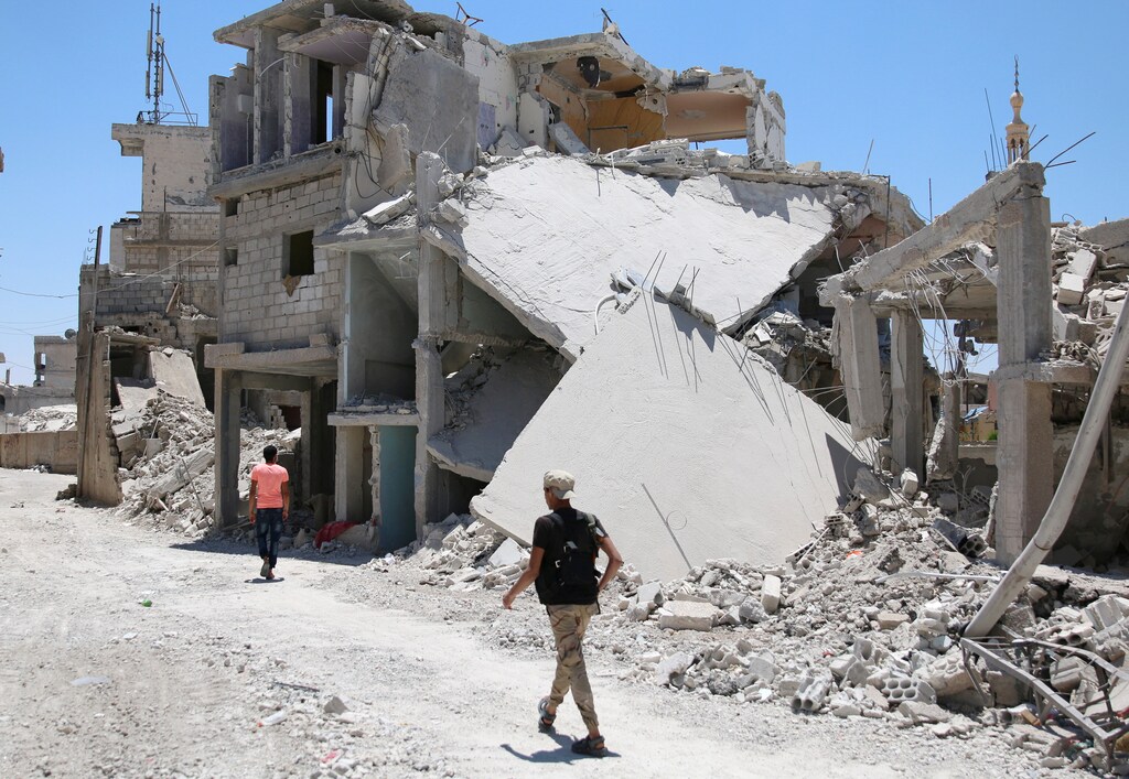 A Free Syrian Army fighter walks past damaged buildings inside a former Palestinian refugee camp in a rebel-held part of the southern city of Deraa, Syria, June 15, 2017. REUTERS/Alaa Al-Faqir - RTS178VG