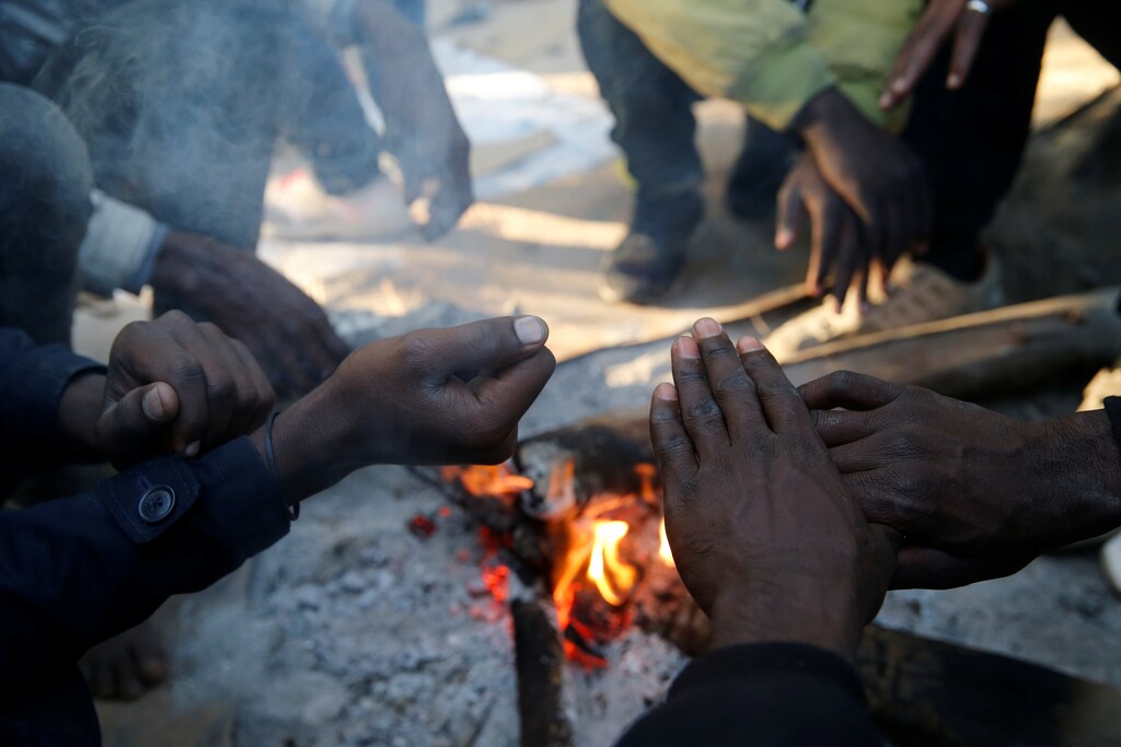 Sudanese migrants warm their hands over a wood fire in Ouistreham, France, October 30, 2017. REUTERS/Pascal Rossignol - RC131FAAA9B0