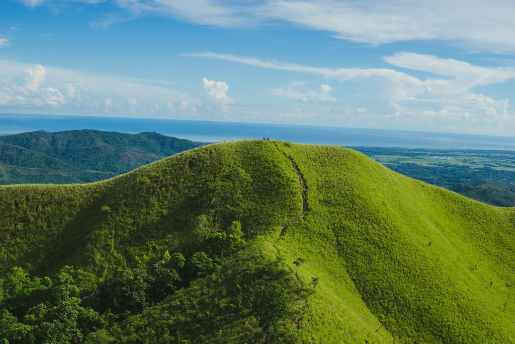 Sabah on Borneo island, green, grassy mountain with sea in the background.