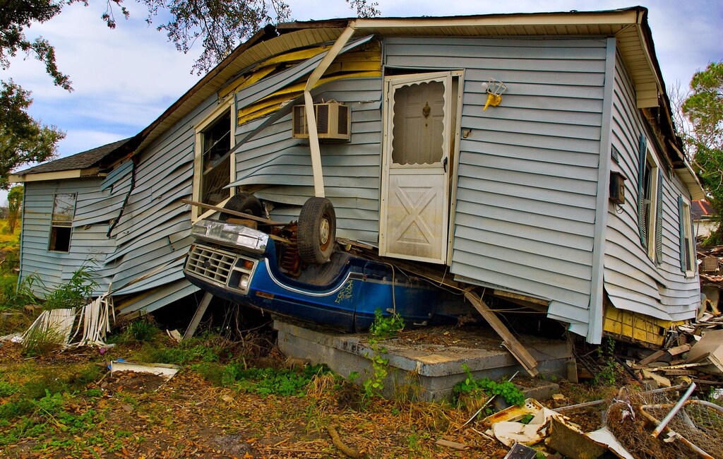 A car underneath a house as a result of a hurricane.
