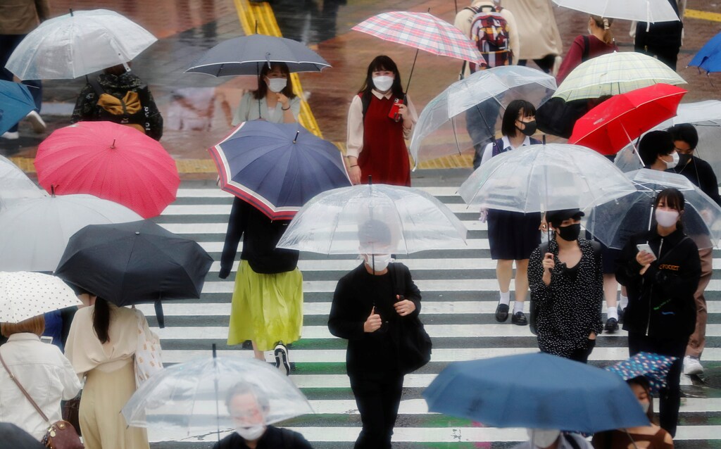 Pedestrians wearing protective masks, following the coronavirus disease (COVID-19) outbreak, makes their way in the rain ahead of the Tokyo 2020 Olympic Games in Tokyo, Japan, May 27, 2021. REUTERS/Kim Kyung-Hoon - RC27ON9NH1BQ