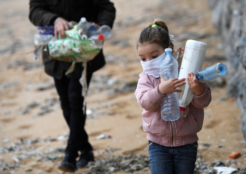 Alexandre and his daughter Alejandra go for a walk and collect plastic along the beach after the restrictions for children were partially lifted for the first time in six weeks, during the outbreak of coronavirus disease (COVID-19) in Gijon, Spain, April 26, 2020. REUTERS/Eloy Alonso - RC2CCG9CX8L5
