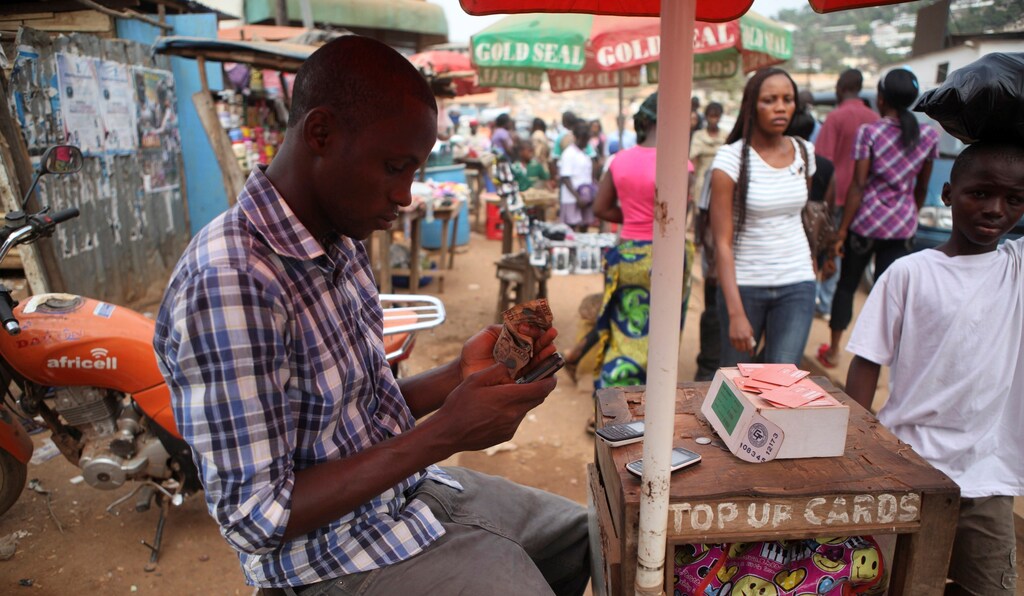 Alpha Abdulai Barrie, a 22-year-old agent for telecoms firm Africell, sits at his stall at Lumley Junction in Sierra Leone's capital Freetown December 13, 2012.