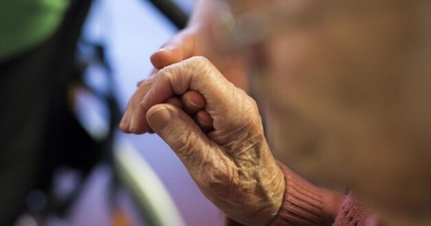 A resident holds the hand of a nurse at the SenVital elderly home in Kleinmachnow outside Berlin May 28, 2013.