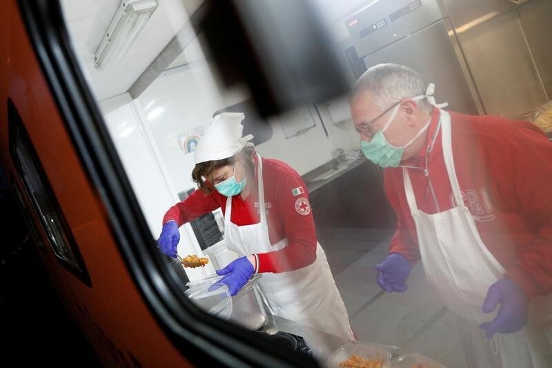 Red Cross workers Sabrina Martellacci, 55, and Gianfranco Amoroso, 58, prepare food for homeless people living on the streets in Rome, Italy, March 17, 2020. Since the coronavirus crisis, Red Cross workers have been increasing their daily activities to meet the growing needs of the homeless in Rome. With nobody around on the streets to give them food or money, and restaurants that would usually donate leftovers closed, homeless are struggling to find food and other supplies to keep them going. REUTERS/Guglielmo Mangiapane - RC2DMF9EH7GK