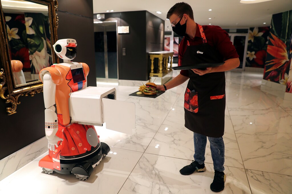 A waiter places food inside a box attached to AI-powered robot Ariel for delivery to a guest at the Hotel Sky, the first in Africa to use automated attendants, in Johannesburg, South Africa, February 9, 2021. Picture taken February 9, 2021.