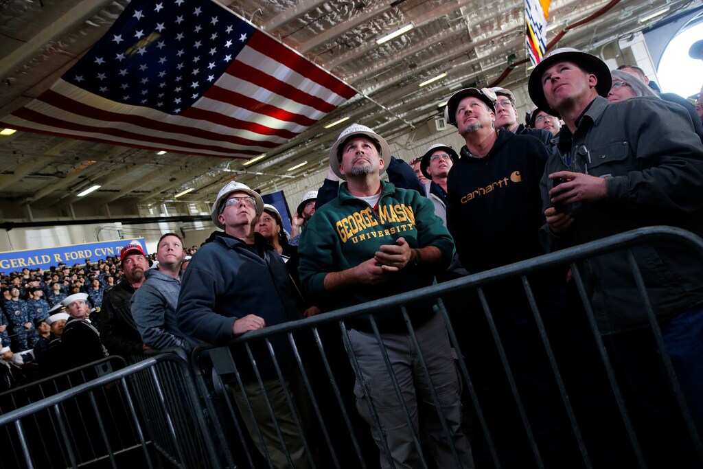 Shipbuilding workers watch on a video screen as U.S. President Donald Trump concludes his remarks aboard the pre-commissioned U.S. Navy aircraft carrier Gerald R. Ford at Huntington Ingalls Newport News Shipbuilding facilities in Newport News, Virginia, U.S. March 2, 2017. REUTERS/Jonathan Ernst - RTS117H0