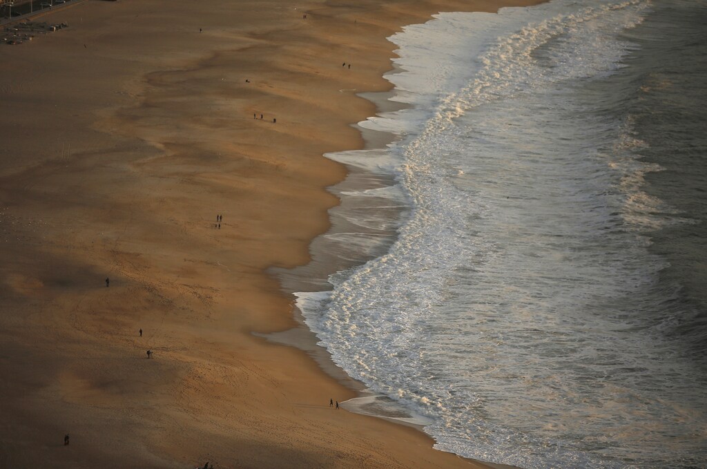 People walk at the beach in Nazare October 29, 2013. REUTERS/Rafael Marchante (PORTUGAL - Tags: SOCIETY) - GM1E9AU0FUD01