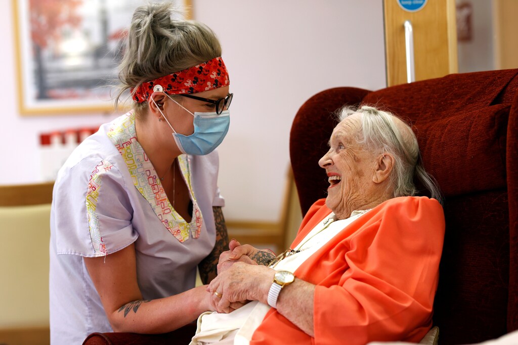 Carer Lucy Skidmore, who remains on site with six colleagues, talks to her 100-year-old great-grandmother and resident Joan Loosley at Fremantle Trust care home, amid the outbreak of the coronavirus disease (COVID-19), in Princes Risborough, Britain, May 5, 2020. REUTERS/Eddie Keogh - RC2IIG9K46EP