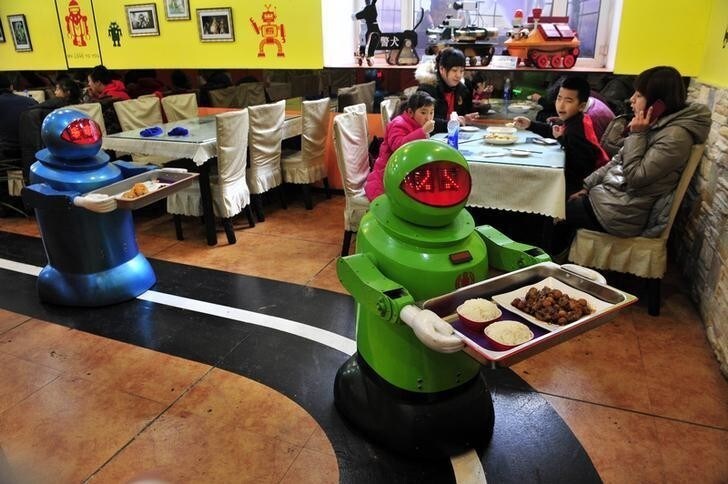 Robots deliver dishes to customers at a Robot Restaurant in Harbin, Heilongjiang province January 12, 2013. Opened in June 2012, the restaurant has gained fame in using a total of 20 robots, which range in heights of 1.3-1.6 metres (4.27-5.25 ft), to cook meals and deliver dishes. The robots can work continuously for five hours after a two-hour charge, and are able to display over 10 expressions on their faces and say basic welcoming sentences to customers, local media reported. REUTERS/Sheng Li (CHINA - Tags: SOCIETY SCIENCE TECHNOLOGY FOOD)