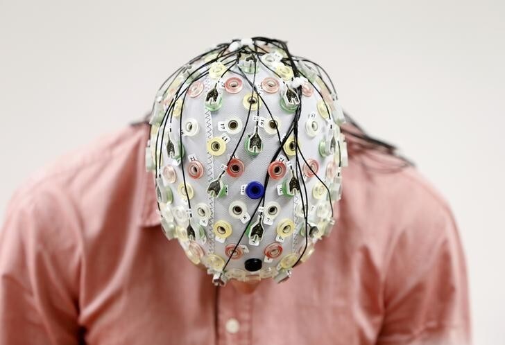 Test person Niklas Thiel poses with an electroencephalography (EEG) cap which measures brain activity, at the Technische Universitaet Muenchen (TUM) in Garching near Munich September 9, 2014. The researchers from TUM and the Technische Universitaet Berlin (team Phypa) try to find ways to control an airplane with computer translated brain impulses without the pilot touching the plane's controls. The solution, if achieved, would contribute to greater flight safety and reduce pilots' workload. Picture taken September 9, 2014. REUTERS/Michaela Rehle