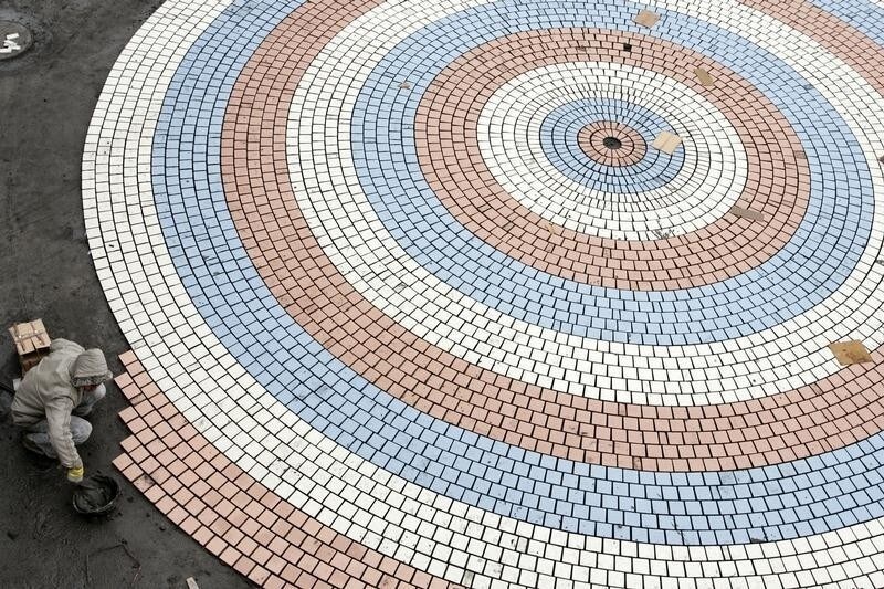 A labourer works on ground tiles outside a stadium in Shanghai January 16, 2007. REUTERS/Aly Song (CHINA) - RTR1L8VL