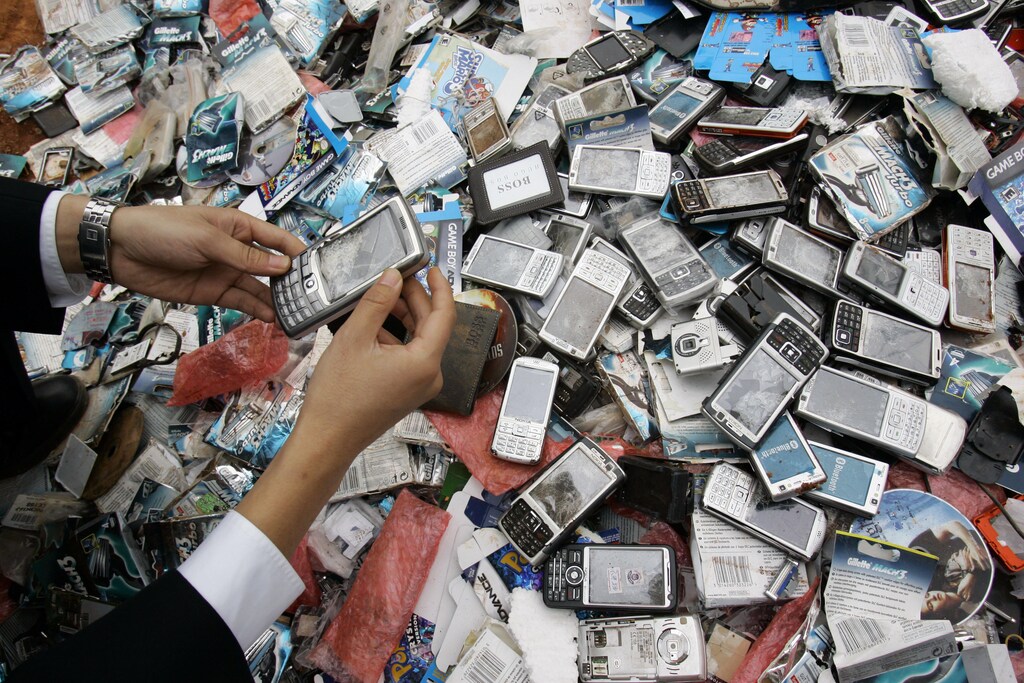 A customs officer displays a counterfeit branded mobile phone at a rubbish dump site in Kunming, Yunnan province April 26, 2010. More than 13,000 confiscated counterfeit branded goods including mobile phones, bags and razors were destroyed during the campaign against piracy, local media reported. REUTERS/Stringer (CHINA - Tags: CRIME LAW BUSINESS) CHINA OUT. NO COMMERCIAL OR EDITORIAL SALES IN CHINA - GM1E64Q19R701