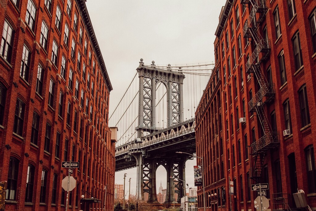 Una instantánea del puente de Brooklyn entre dos edificios de ladrillo rojo.