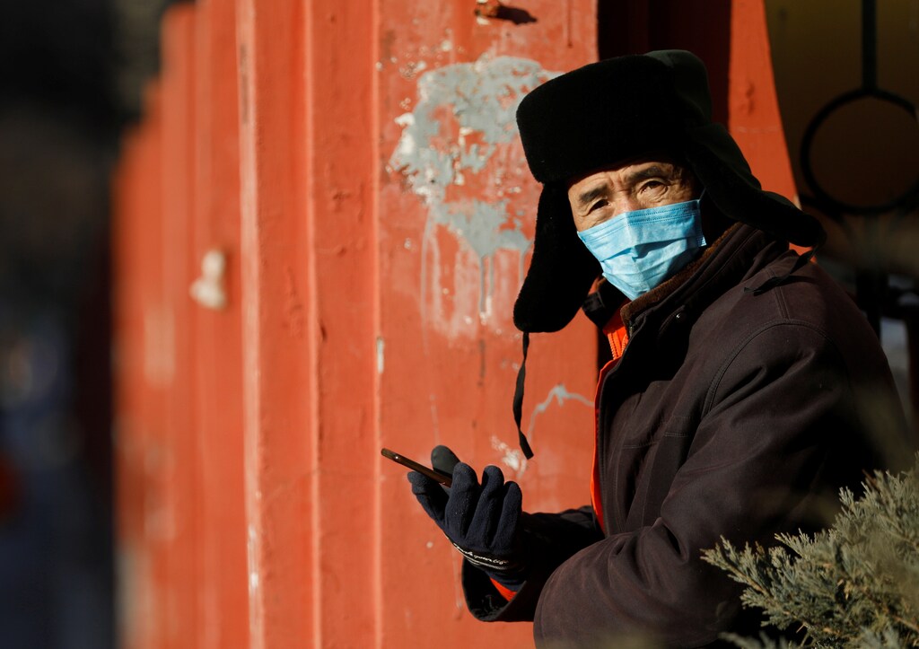 A man wearing a face mask uses his phone on a winter day, following the coronavirus disease (COVID-19) outbreak, in Beijing, China, December 21, 2020. REUTERS/Tingshu Wang - RC2FRK93E958