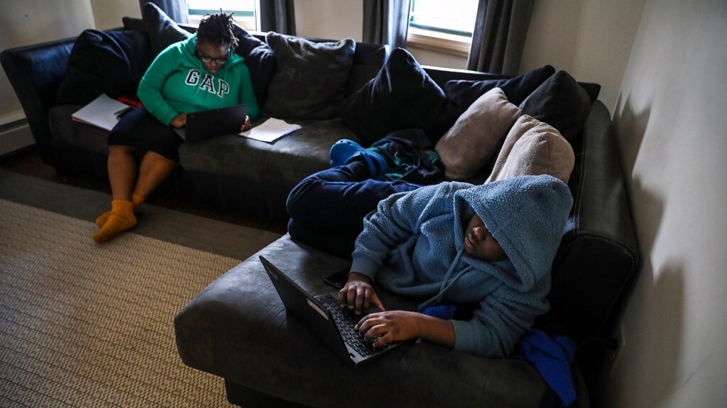 A sixth grader completes his homework online in his family’s living room in Boston on March 31, 2020.