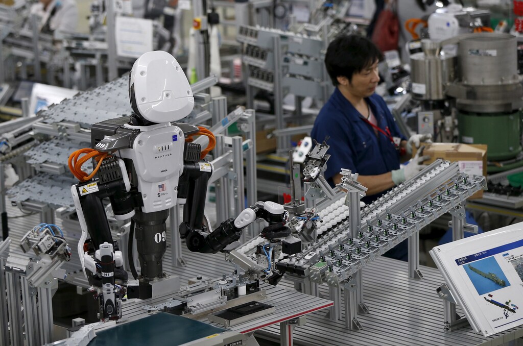 A humanoid robot works side-by-side with employees in the assembly line at a Japanese factory