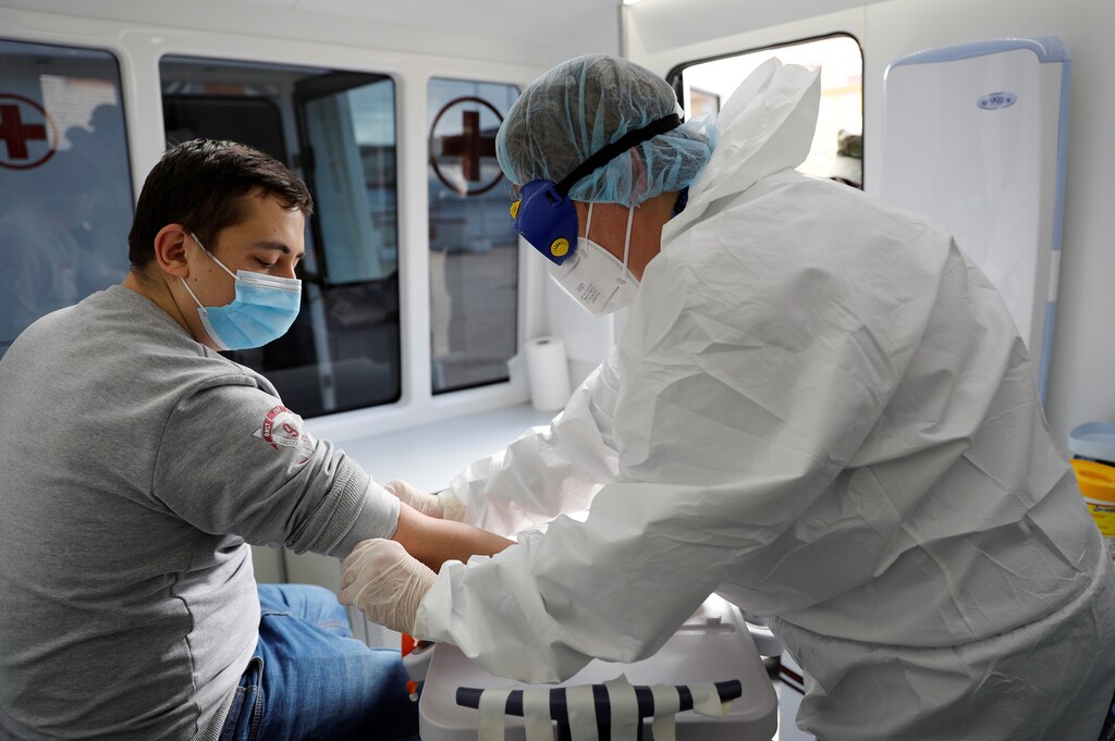 A medical specialist wearing personal protective equipment (PPE) takes a blood sample from a conscript to test for the coronavirus disease (COVID-19) at a recruiting station in Kaliningrad, Russia May 20, 2020. REUTERS/Vitaly Nevar - RC2ISG9RY3E3