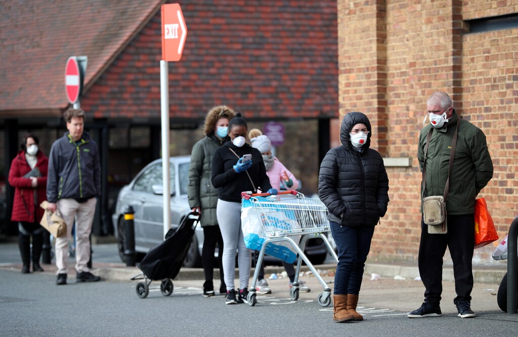 People wearing protective facemasks queue outside Sainsbury's supermarket in Streatham, as the spread of the coronavirus disease (COVID-19) continues, London, Britain, March 29, 2020. REUTERS/Hannah McKay - RC2NTF94H09S