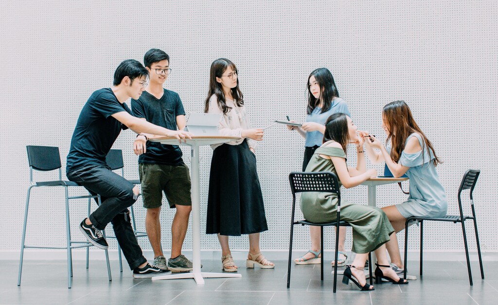 six students around a laptop and tables