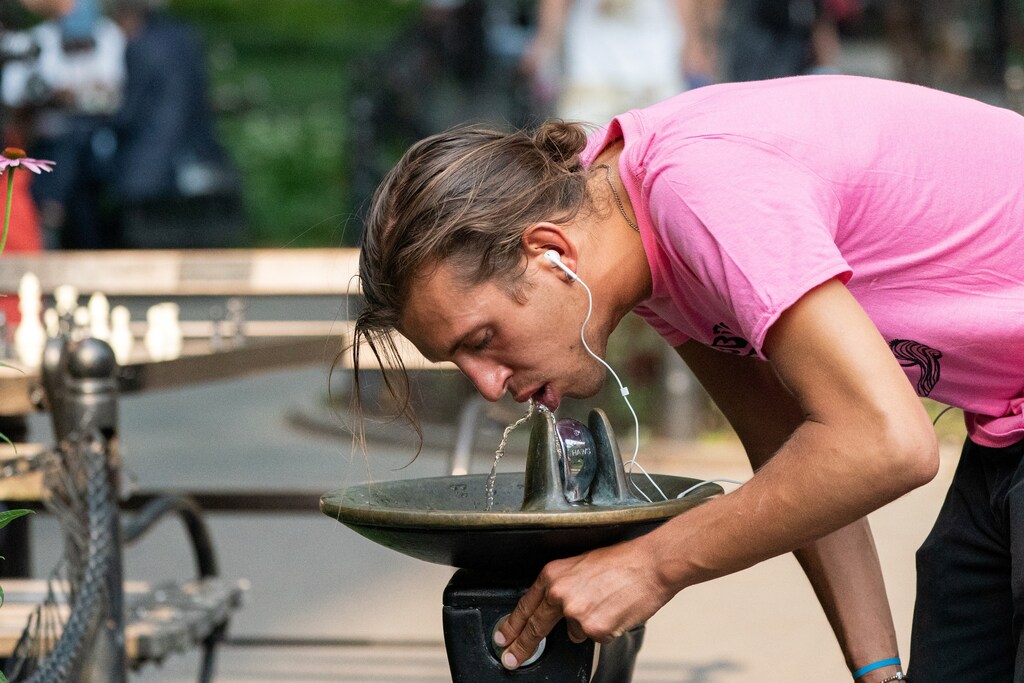 A man drinks from a water fountain in Washington Square park during a heatwave in New York City.