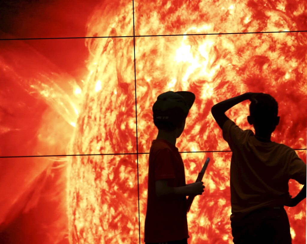 Two boys at the Smithsonian National Air and Space Museum look at images that are 48 hours old, coming back from the sun, in Washington, September 1, 2015. The sun's images, from NASA's Solar Dynamic Observatory, show four different wavelengths and deliver data on the sun's influence on earth. REUTERS/Gary Cameron - RTX1QN1Q