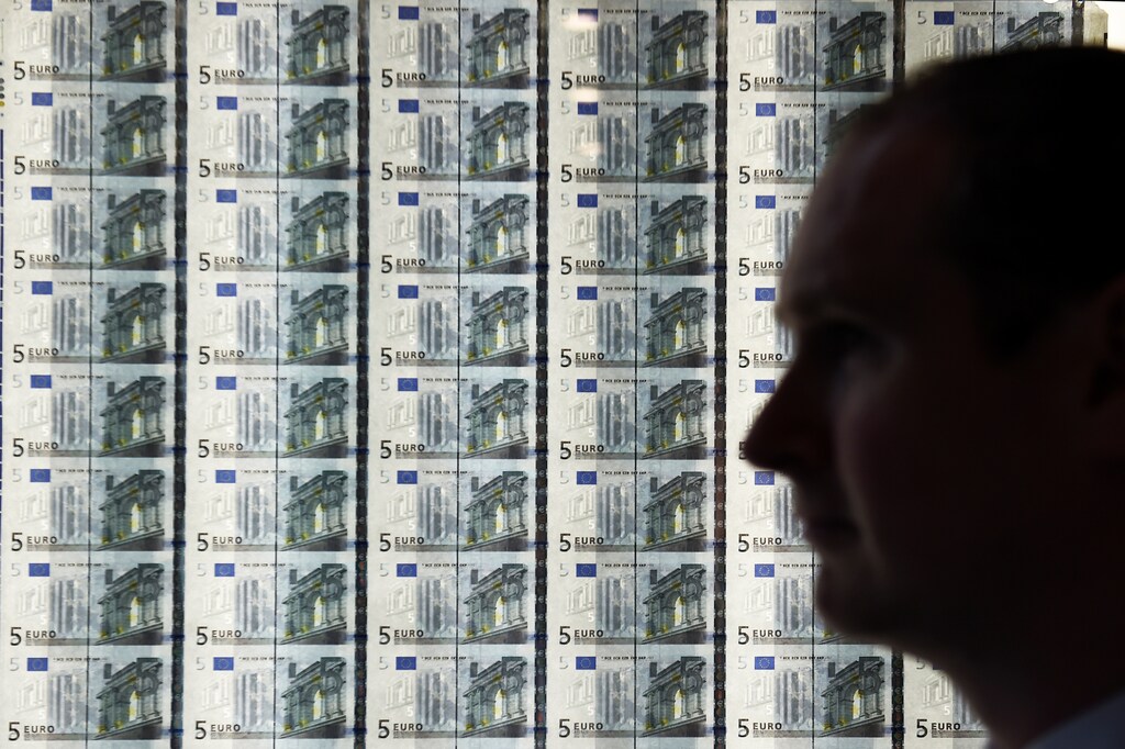 A man walks by a sheet of 5-euro notes at the opening of the new Central Bank of Ireland offices in Dublin.