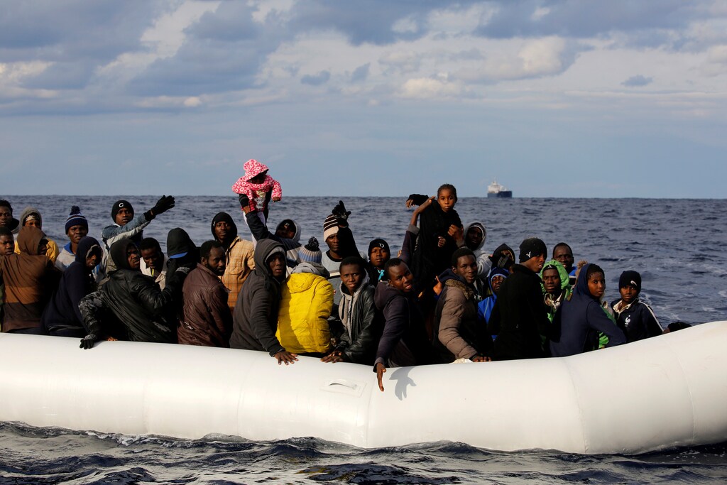Migrants lift up children on an overcrowded raft, before lifeguards from the Spanish NGO Proactiva Open Arms rescue all 112 on aboard, including two pregnant women and five children, as it drifts out of control in the central Mediterranean Sea, some 36 nautical miles off the Libyan coast January 2, 2017. REUTERS/Yannis Behrakis - RTX2X8IA
