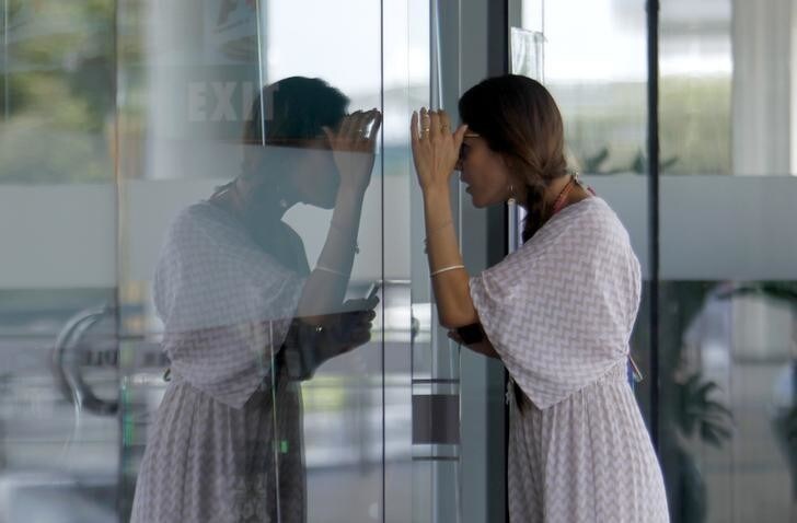 Jessica Michibata, girlfriend of McLaren Formula One driver Jenson Button, looks through the glass door of the media centre during the third practice session of the Malaysian F1 Grand Prix at Sepang International Circuit outside Kuala Lumpur, March 23, 2013. REUTERS/Samsul Said (MALAYSIA - Tags: SPORT MOTORSPORT F1 FASHION)