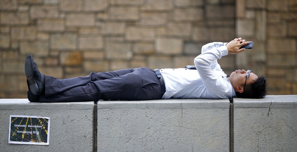 A businessman relaxes on a barrier between closed roads in the part of Hong Kong's financial central district pro-democracy protesters are occupying October 31, 2014.