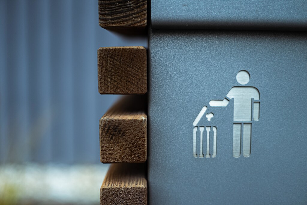 A close-up on the symbol of a person throwing rubbish into an open bin.