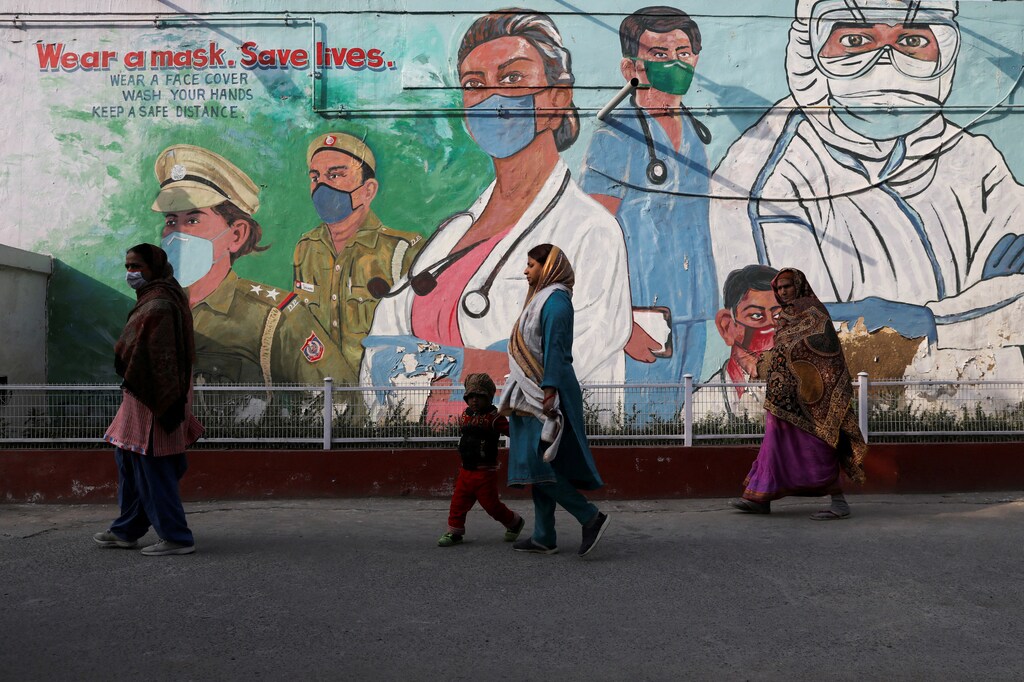 FILE PHOTO: Women walk past a mural amidst the spread of the coronavirus disease (COVID-19) in New Delhi, India, February 7, 2022. REUTERS/Anushree Fadnavis/File Photo