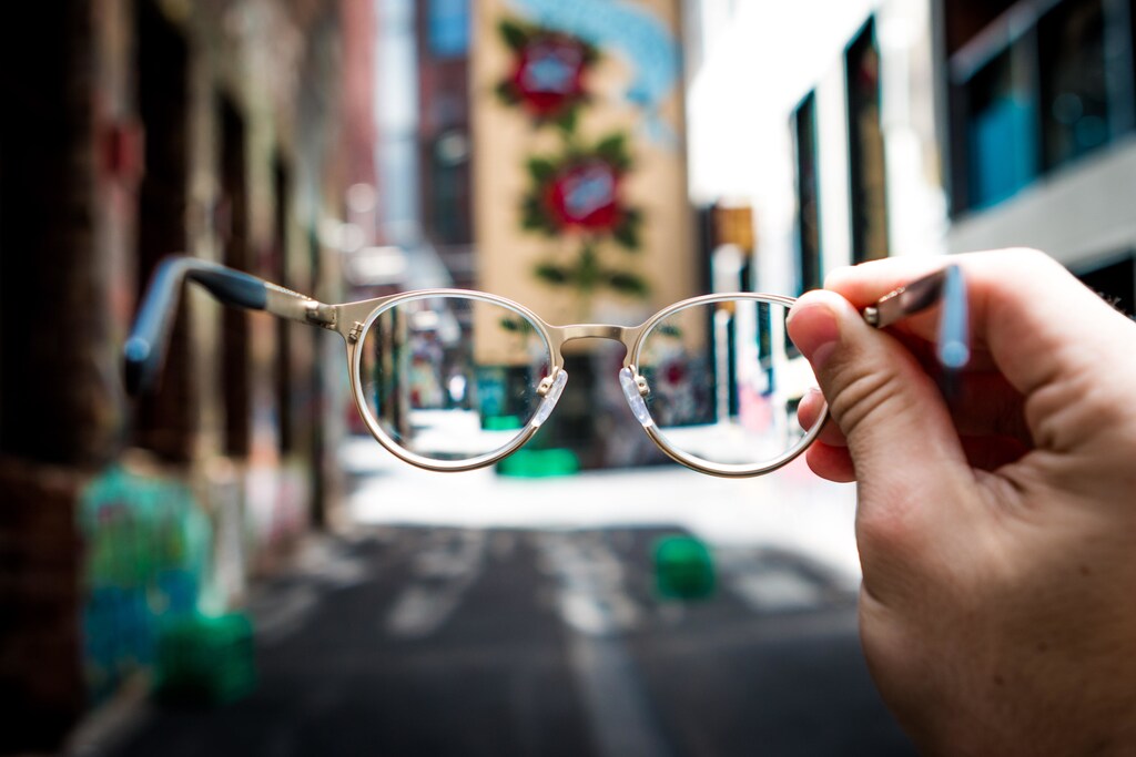 Person holding glasses in a street.