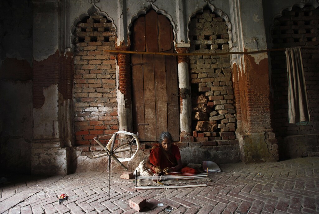 A woman spins cotton thread on a charkha (spinning wheel) in the courtyard of a temple in the northern Indian town of Ayodhya September 22, 2010. A court will rule on Friday whether Hindus or Muslims own land around a demolished mosque in Ayodhya in a bid to settle a dispute that in 1992 sparked some of the worst riots since the sub-continent's partition. REUTERS/Adnan Abidi (INDIA - Tags: POLITICS RELIGION SOCIETY) - GM1E69M1PFJ01