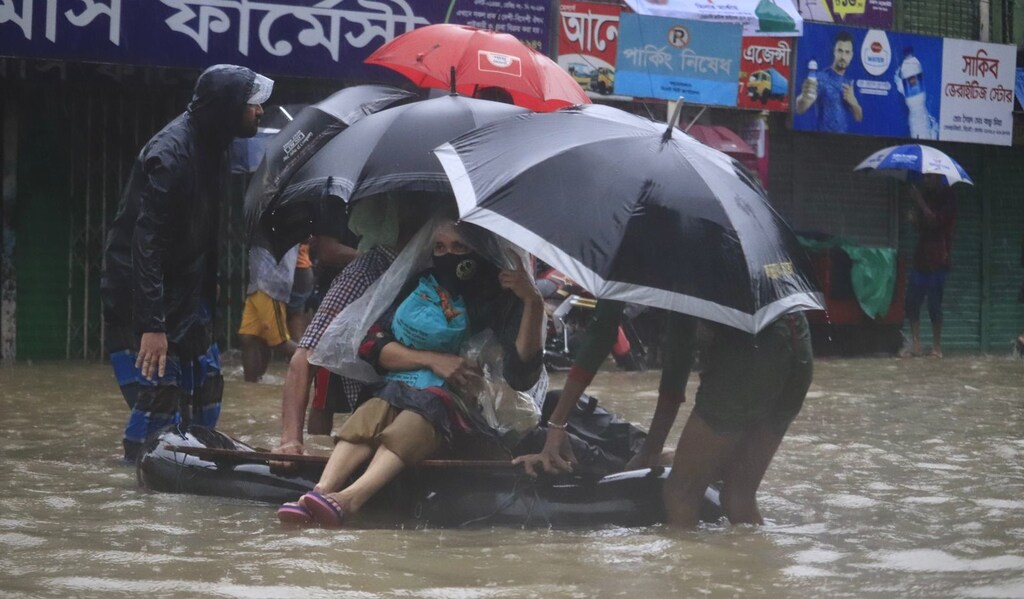 climate adaptation: neighbours help to transport a family in Sylhet to a temporary shelter on an improvised boat made from an inflated tube, after the family's home was flooded during the worst flood to hit northern Bangladesh in decades, in June 2022.