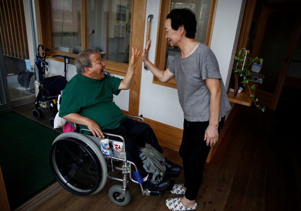 Congenital Minamata disease patient Isamu Nagai high-fives a caretaker as he arrives at Oruge-Noa, a group care home for disabled people including Minamata disease patients, in Minamata, Kumamoto Prefecture, Japan, September 13, 2017. Nagai was born in 1957 and cannot walk due to congenitally deformed legs
