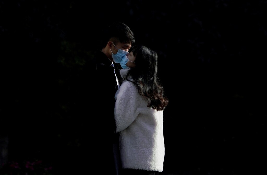 A couple wearing masks kiss at a main shopping area, in downtown Shanghai, China, as the country is hit by an outbreak of a new coronavirus, February 16, 2020.