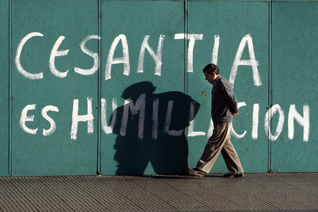 A man walks past graffiti that reads "unemployment is humiliation" in downtown Santiago February 11,2009. REUTERS/Ivan Alvarado (CHILE) - RTXBHNU