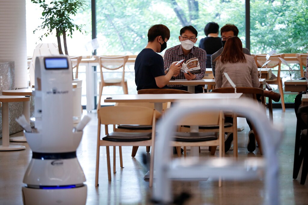 Customers wait at a cafe where a robot that takes orders, makes coffee and brings the drinks straight to customers is being used in Daejeon, South Korea, May 25, 2020. REUTERS/Kim Hong-Ji - RC2FVG9HKKJ0