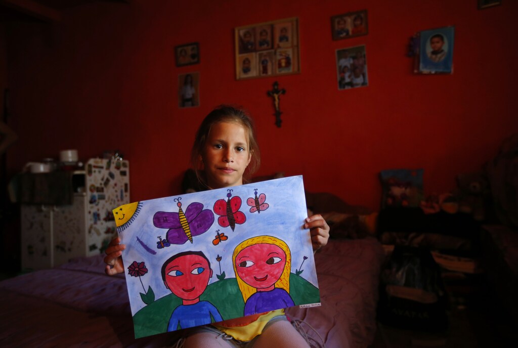 Diana Mohacsi, a Hungarian Roma, poses with her artwork at her home in the village of Told, in eastern Hungary June 21, 2013. The Igazgyongy (Pearl) art education foundation teaches art classes in the area and tries to give underprivileged children, most of them Roma, a chance to break out of hopeless poverty by building their self-esteem and giving them a goal in life. REUTERS/Laszlo Balogh (HUNGARY - Tags: EDUCATION SOCIETY POVERTY) - GM1E96L1PLI01