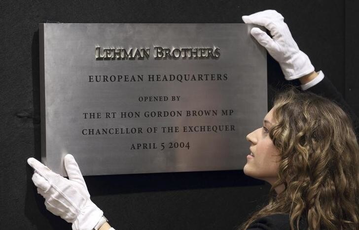 A Christie's employee poses for a photograph with the plaque from Lehman Brothers' European headquarters at Christie's in central London, September 24, 2010. Various items are on display before the auction of Lehman Brothers: Artwork and Ephemera, which will take place on September 29. REUTERS/Andrew Winning (BRITAIN - Tags: ENTERTAINMENT BUSINESS SOCIETY)
