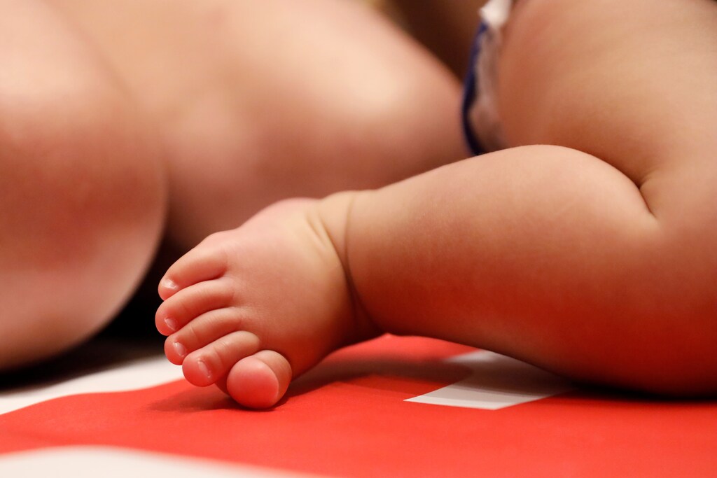 A baby's foot is seen next to his mother before competing in the 2018 "Diaper Derby" crawling race, a promotion event ahead of the New York City Triathlon, in Manhattan, New York, U.S., June 29, 2018. REUTERS/Shannon Stapleton - RC1A37EB8980