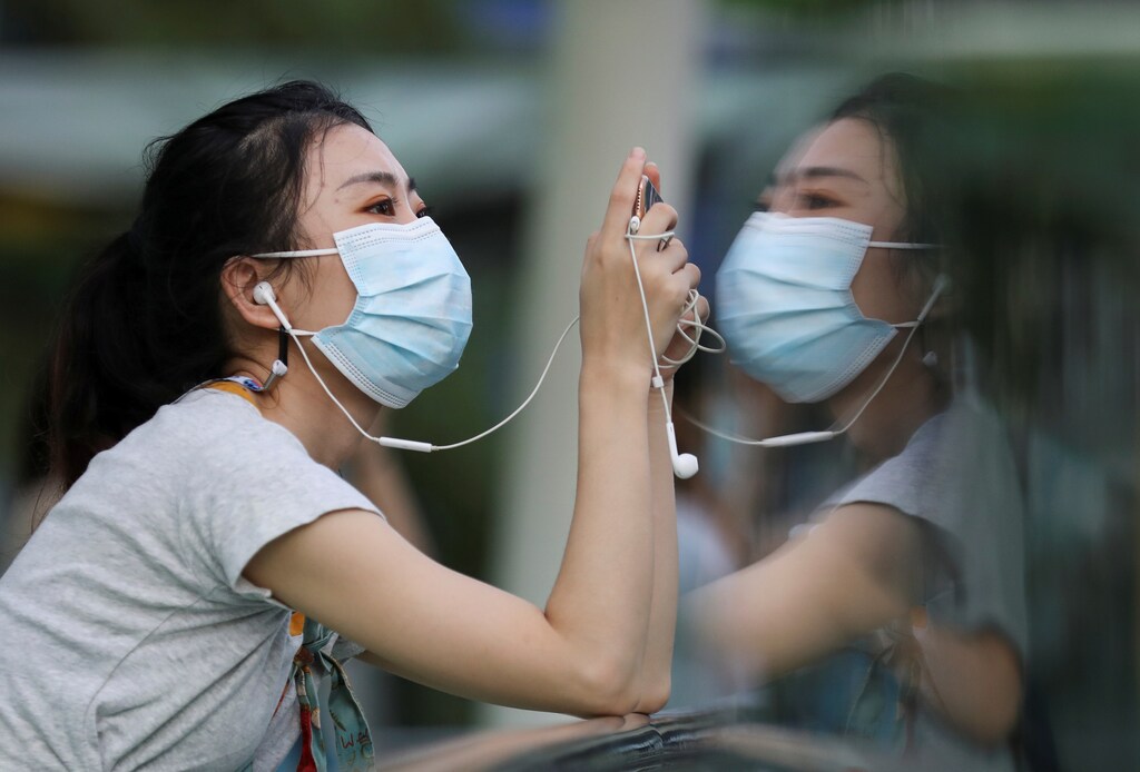 A woman wears a protective face mask as she looks at her mobile phone amid the outbreak of the coronavirus disease (COVID-19), in Bangkok, Thailand September 30, 2020. REUTERS/Soe Zeya Tun - RC219J9B1TR3